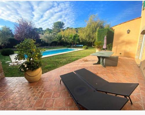 une terrasse avec une piscine, une table et un banc dans l'établissement Propriété Maria avec grande piscine, à Vallauris