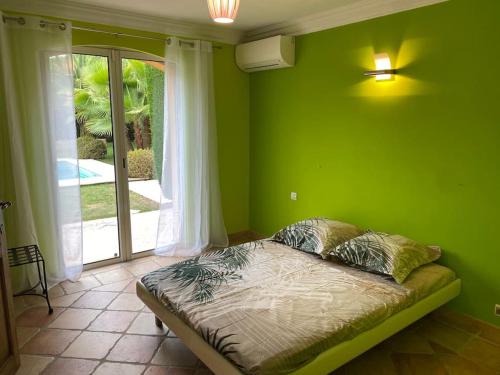 Cette chambre verte comprend un lit et une fenêtre. dans l'établissement Propriété Maria avec grande piscine, à Vallauris