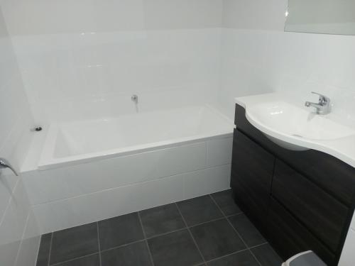 La salle de bains est pourvue d'un lavabo et d'une baignoire. dans l'établissement French Corner Apartments, à Dubbo