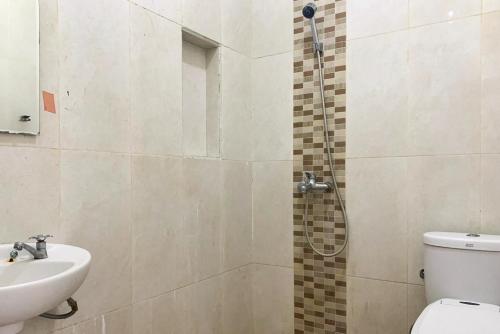 a bathroom with a shower and a toilet and a sink at Urbanview Hotel Villa Q Gisting by RedDoorz in Banjarnegeri