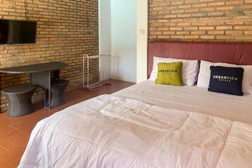 a bedroom with a large white bed with a brick wall at Urbanview Hotel Villa Q Gisting by RedDoorz in Banjarnegeri