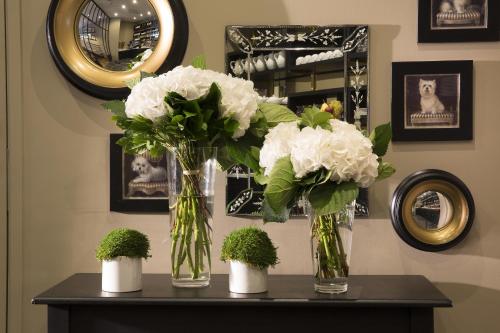 two vases with white flowers and plants on a table at Le Nemours Rennes in Rennes