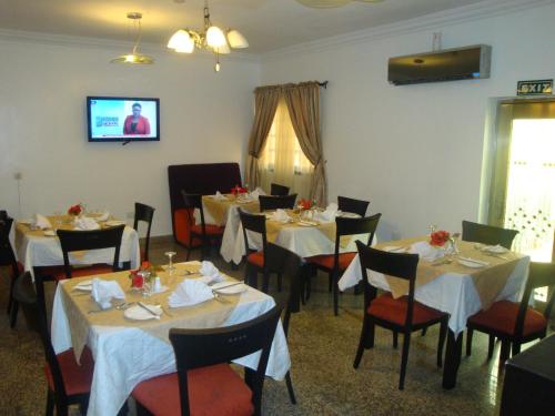 a dining room with tables and chairs and a tv at Suru Express Hotel GRA in Ikeja