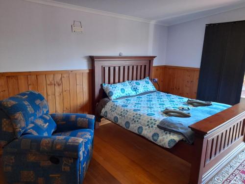 een slaapkamer met een bed en een stoel bij Three Bedroom Escape with Room to Roam in Rocky Cape