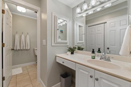 Baño blanco con lavabo y espejo en Water Front Condo with Boat Slip: The Dock House, en Elizabeth City