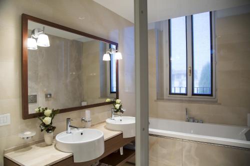 a bathroom with two sinks and a tub and a mirror at Grand Hotel Terme Sirmione in Sirmione