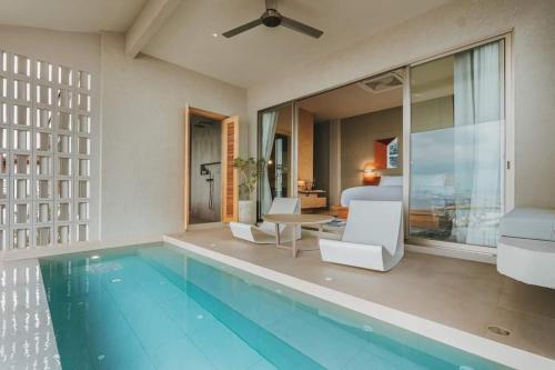 una piscina con sillas blancas y un dormitorio en อาทิตย์ รีสอร์ท เกาะล้าน en Ko Larn