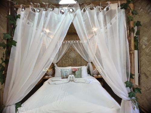 a bedroom with a canopy bed with white curtains at Hidden Haven Coron in Coron