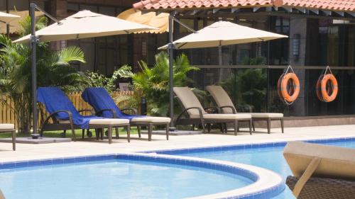 a swimming pool with chairs and umbrellas next to a building at Tang Palace Hotel in Accra