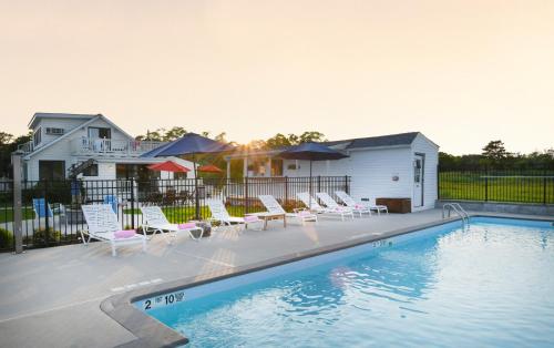 a swimming pool with chairs and a house at Bayview Resort in Hampton Bays