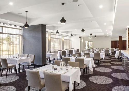 a dining room with white tables and chairs at Mid City Motel Warrnambool in Warrnambool