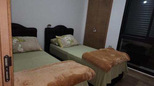 um quarto com 2 camas individuais e uma janela em Plage dès nations 2 bedroom apartment with backyard view em Sidi Bouqnadel