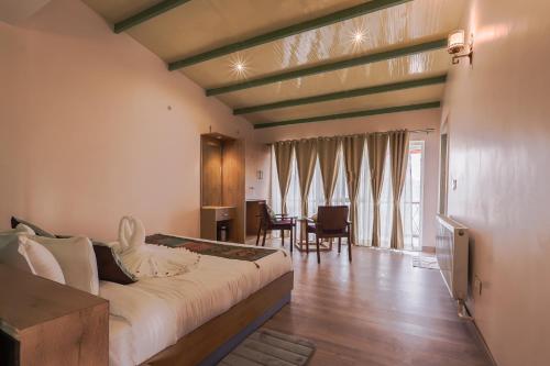 1 dormitorio con 1 cama grande y comedor en Adrushya- Suites & Villas by MLS en Mukteswar