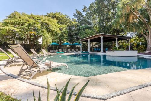 a swimming pool with chairs and a gazebo at Casona de Elefantes Boutique Hotel in Cuernavaca