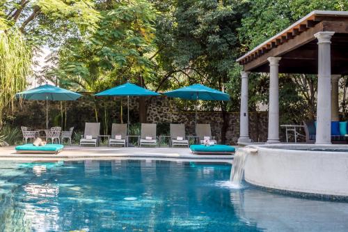 a swimming pool with umbrellas and chairs and a pool at Casona de Elefantes Boutique Hotel in Cuernavaca