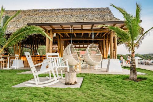 a pavilion with white chairs and palm trees in the grass at Ocean View Apartment - Blue Venao in Playa Venao