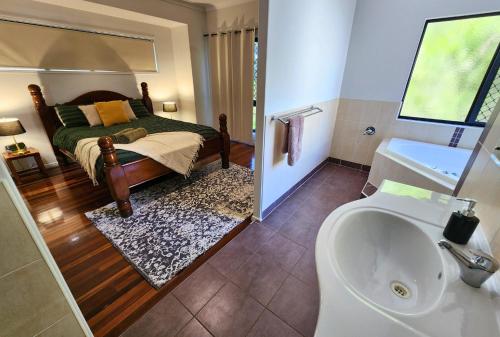 a bathroom with a bed and a sink and a tub at EUROLIE ON HIGH at Kingfisher Bay Fraser Island in Kingfisher Bay