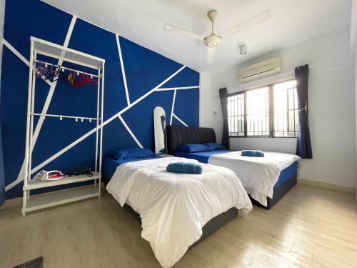 1 dormitorio con 2 camas y pared azul en Cozzzzy Two Next to Axiata Arena, Bukit Jalil en Kuala Lumpur