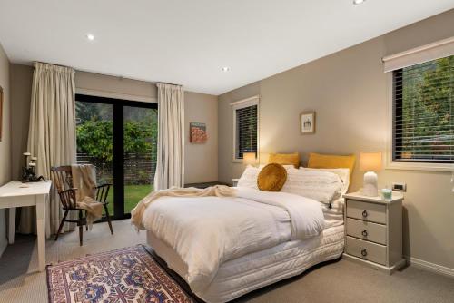 a bedroom with a large bed and a desk at Acer Cottage - Beautiful Luxury Home - Arrowtown in Arrowtown