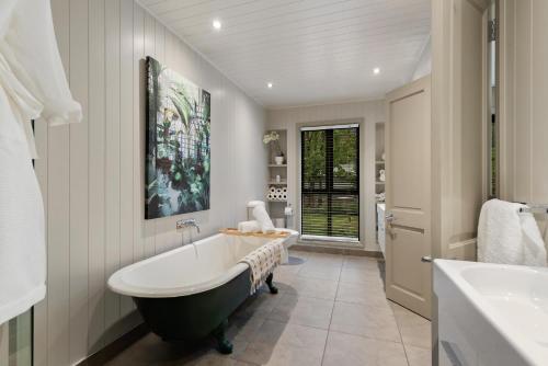a bathroom with a bath tub and a sink at Acer Cottage - Beautiful Luxury Home - Arrowtown in Arrowtown
