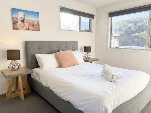a bedroom with a large bed with two windows at Iron Bark Chalet in Crackenback