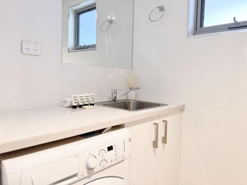 a white kitchen with a sink and a dishwasher at Iron Bark Chalet in Crackenback