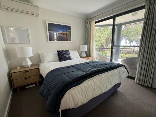 a bedroom with a large bed and a balcony at 5@CapeView, beachfront Geographe Bay in Busselton