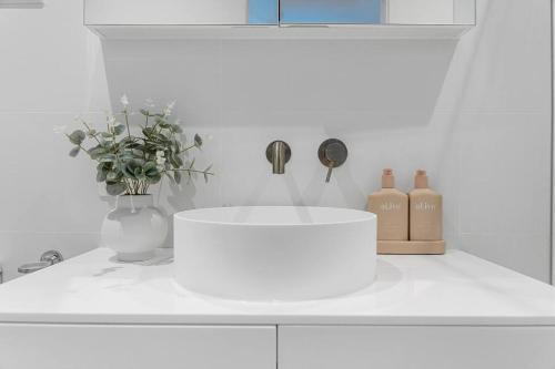 a kitchen counter with a white sink and a vase with flowers at Toowoon Bay - Tranquil Couples Retreat - EV Powerpoint in Long Jetty