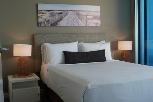 a bedroom with a white bed and two lamps at Silvershore Apartments on the Broadwater in Gold Coast