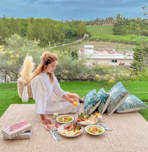a woman sitting on a picnic table with plates of food at SOL Glamping at Khao yai in Ban Nong Makha