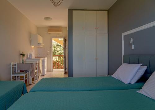 a bedroom with two beds and a kitchen with a table at Diona Studios in Lourdhata