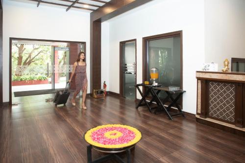 a woman walking in a living room with a rug on the floor at The Greenfields Resort and Convention in Venkatāpur