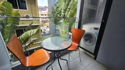a balcony with a table and two chairs and a window at Tropical Garden A Studio in Pattaya South