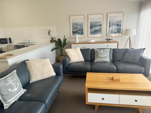 a living room with two blue couches and a table at BlueWater Apartments in Merimbula