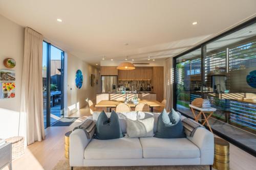 a living room with a white couch with pillows at Waiata Beach House - Onetangi in Onetangi