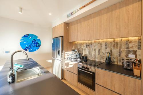 a kitchen with wooden cabinets and a stainless steel refrigerator at Waiata Beach House - Onetangi in Onetangi