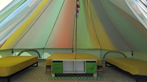 a tent with two beds and a table in it at Belle Village, non electric ,Rent a bell tent, BEDDING NOT SUPPLIED in Narberth