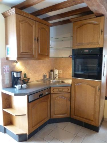 a kitchen with wooden cabinets and a sink at gîte Le cheval ardennais in Gouvy