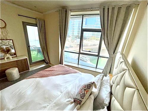a bedroom with a bed and a large window at Wonderful two bed room with full marina view in Dubai