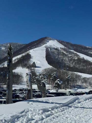 a snow covered mountain with cars parked in a parking lot at Yama Lodge Madarao in Madarao Kogen