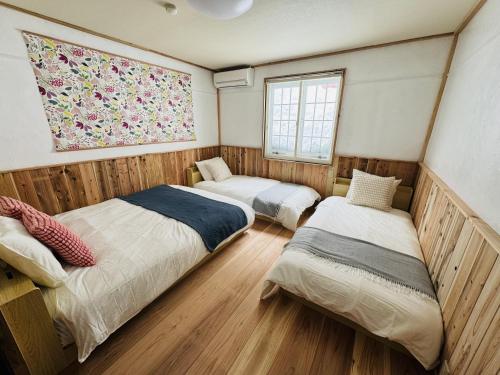 a bedroom with two beds and a painting on the wall at Yama Lodge Madarao in Madarao Kogen