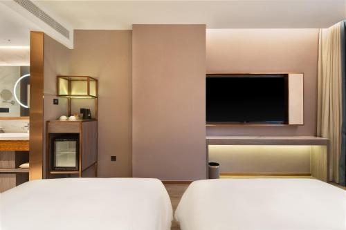 a hotel room with two beds and a flat screen tv at 朗丽兹酒店深圳罗湖口岸店 in Shenzhen