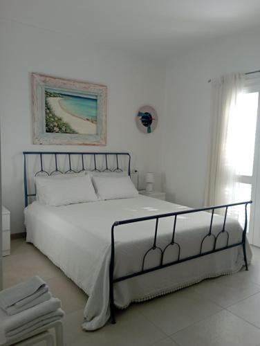 un letto in una camera bianca con una foto sul muro di Sea & Country Rooms a Golfo Aranci