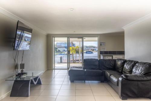 a living room with a leather couch and a table at Unbeatable Waterfront Location in Sussex inlet