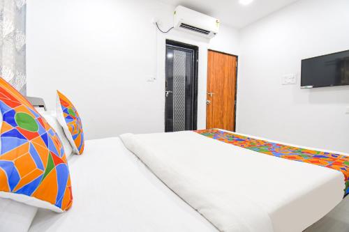 a bedroom with two beds and a tv on a wall at FabHotel Silver 7 Homes in Hinjewadi