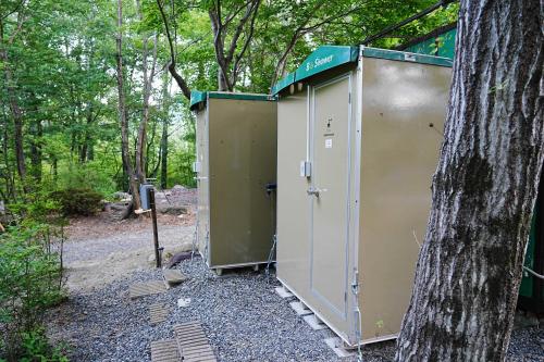 two portable toilets sitting next to a tree at Glamping Azumino BASE ポレキャン in Aoki-gemi