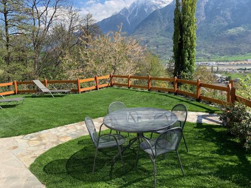 a table and chairs on a lawn with mountains in the background at L'armonia della natura in Aosta