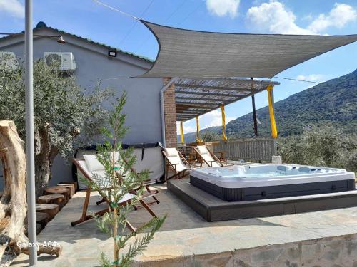 a patio with a jacuzzi tub and a house at Elaia Rest House in Fréngaina