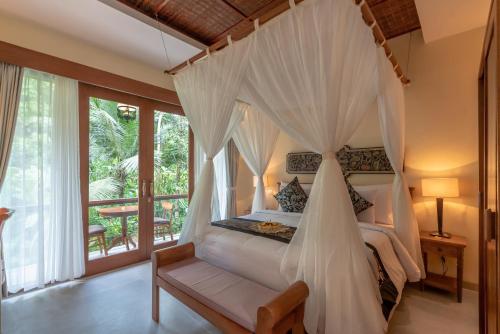 um quarto com uma cama e uma rede mosquiteira em The Compass Rose Ubud em Ubud