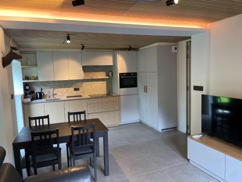 une cuisine et une salle à manger avec une table et une télévision dans l'établissement La Corniche, à Brides-les-Bains